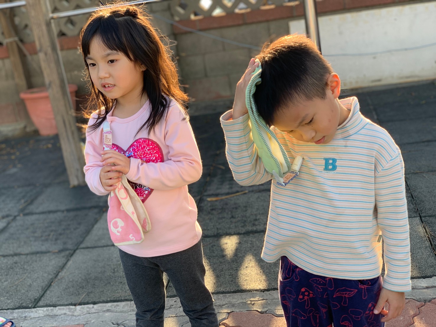 兩名孩子在戶外使用手帕短夾,男孩拿起布巾時短夾仍連接衣物