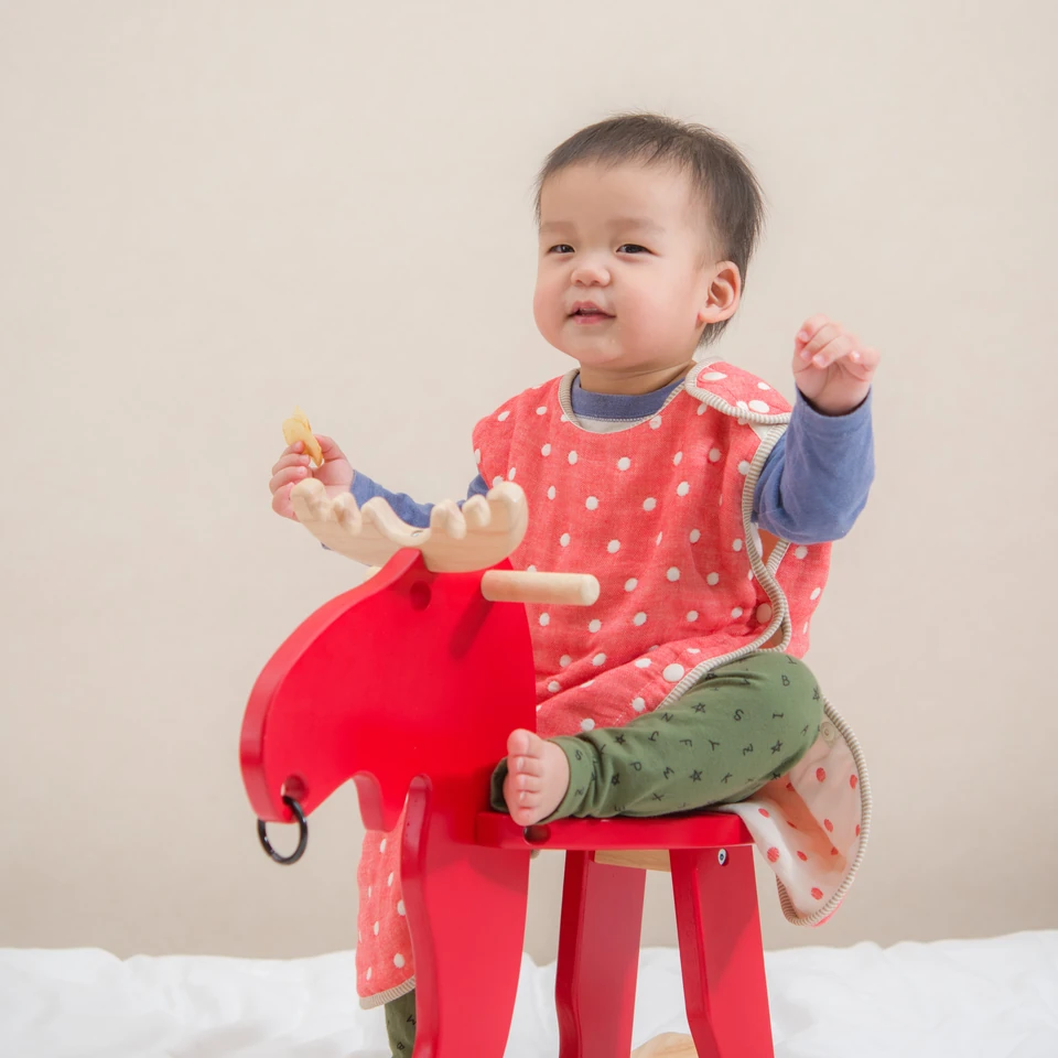 孩子穿著紅底白點六重紗防踢被坐在木馬上，為系列穿著示意