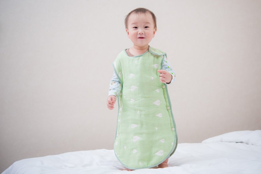 孩子穿著綠色六重紗防踢被，肩部與側邊按扣清楚可見